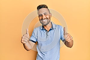 Handsome man with beard wearing casual clothes approving doing positive gesture with hand, thumbs up smiling and happy for success photo