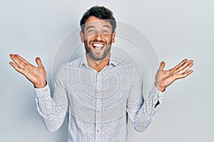 Handsome man with beard wearing casual elegant shirt celebrating victory with happy smile and winner expression with raised hands