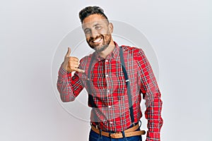 Handsome man with beard wearing hipster elegant look smiling doing phone gesture with hand and fingers like talking on the