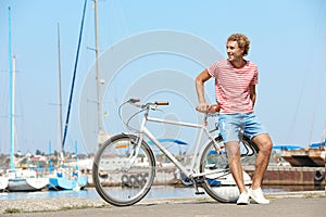 Handsome man with bicycle at pier