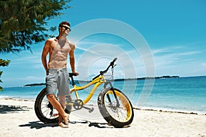 Handsome Man With Bike Sun Tanning On Beach. Summer Vacation.