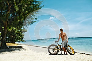 Handsome Man With Bike Sun Tanning On Beach. Summer Vacation.