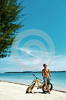 Handsome Man With Bike Sun Tanning On Beach. Summer Vacation.