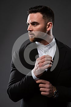 A handsome man in a black suit and white shirt. Businessman standing on a black background