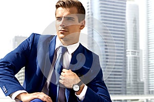 Handsome man in a blue suit against a city background on a sunny day