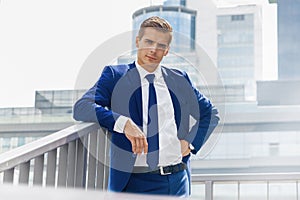 Handsome man in a blue suit against a city background on a sunny day