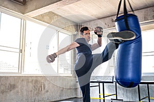 Handsome man in boxing gloves punching bags exercise in fitness gym