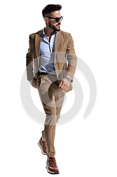 Handsome man in brown suit looking to side and walking