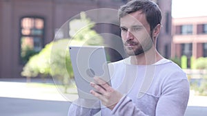 Handsome Man Browsing Internet on Tablet Computer while Standing Outside