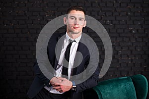 Handsome man in a business suit against a black brick wall, model photo. Succesful fashionable man