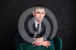 Handsome man in a business suit against a black brick wall, model photo. Succesful fashionable man
