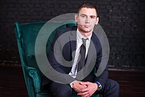 Handsome man in a business suit against a black brick wall, model photo. Succesful fashionable man