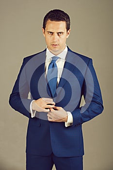 Handsome man buttoning button on elegant blue formal suit jacket