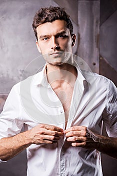 Handsome man buttoning shirt.