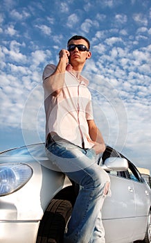 Handsome man calling by cellular phone near car