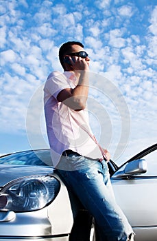 Handsome man calling by cellular phone near car