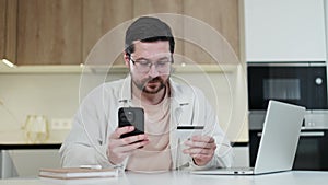 Handsome man with card engaging in online purchasing through personal smartphone