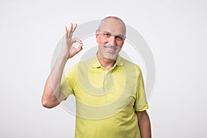 A handsome man in checkered shirt isolated on gray background showing ok sign