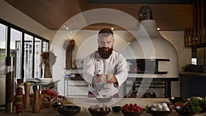 Handsome man chef cooking bakery in kitchen. Baker hands sifting flour in cafe.