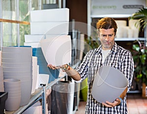 Handsome man choosing pots for flowers and trees in gardening market