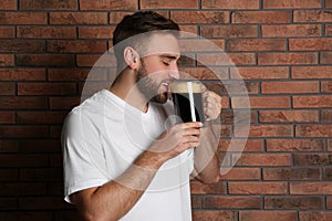 Handsome man with cold kvass near wall. Traditional Russian summer drink