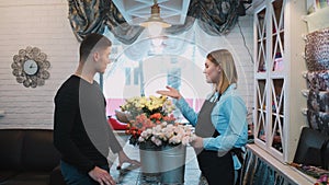 Handsome man come to a flower shop and ask florist about flowers