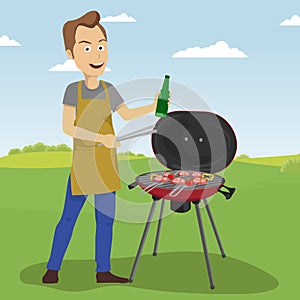Handsome man cooking barbecue grill outdoors holding a bottle and tongs