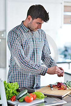 Handsome man cooking at home preparing salad in kitchen.