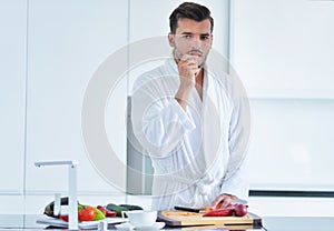 Handsome man cooking at home preparing salad in kitchen.