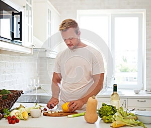 Handsome man cooking at home preparing salad in kitchen