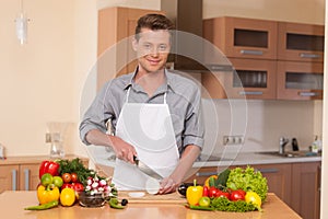 Handsome man cutting onion on chopping board.