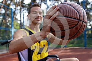 Handsome man with disability playing basketball in wheelchair