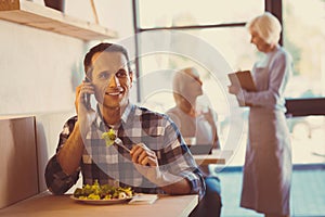 Handsome man discussing work on phone while eating out