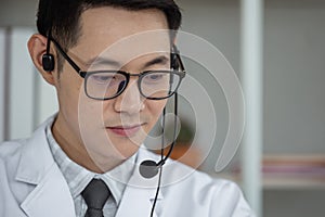 Handsome man doctor speaking microphone with headset to patient at work in home office, online conference.