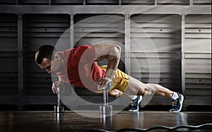 Handsome man doing push ups exercise with one hand in fitness gym