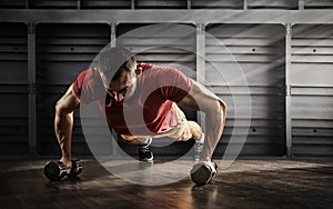 Handsome man doing push ups exercise with one hand in fitness gym