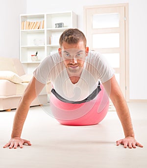 Handsome man doing push ups on the gym ball