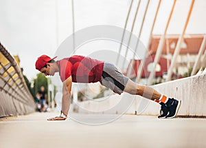 Handsome man doing push-ups outdoors on sunny day.