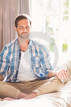 Handsome man doing yoga on his bed