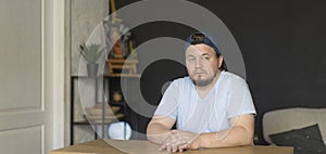 Handsome man dressed in jeans cap sitting at home desk.