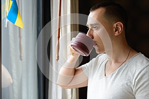 Handsome man drinking coffee and looking out the window