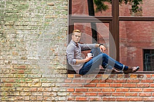 Handsome man drinking coffee outside of office building