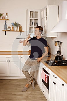 Handsome man drinking coffee or tea at home in the kitchen. Morning routine concept