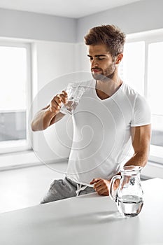 Handsome Man Drinking Glass Of Fresh Water Indoors In Morning