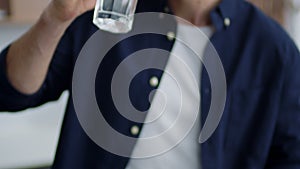 Handsome man drinking water at home kitchen. Male hands pouring water into glass