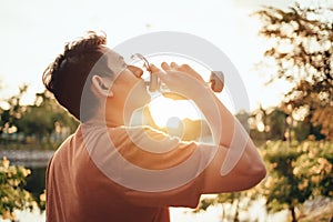 Handsome man drinking water on a sunny day after running. Sport, fitness workout concept