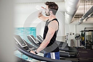 Handsome man drinking water on treadmill