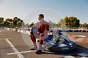 Handsome man driver sitting at his go-kart car waiting for start of competition