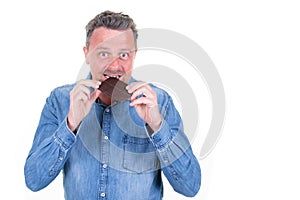 Handsome man eating bitting a chocolate bar aside copy space white background