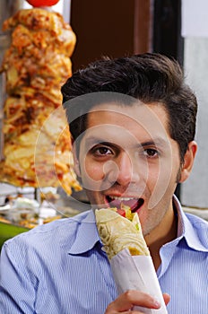 Handsome man eating a delicious shawarma with chicken and lamb meat